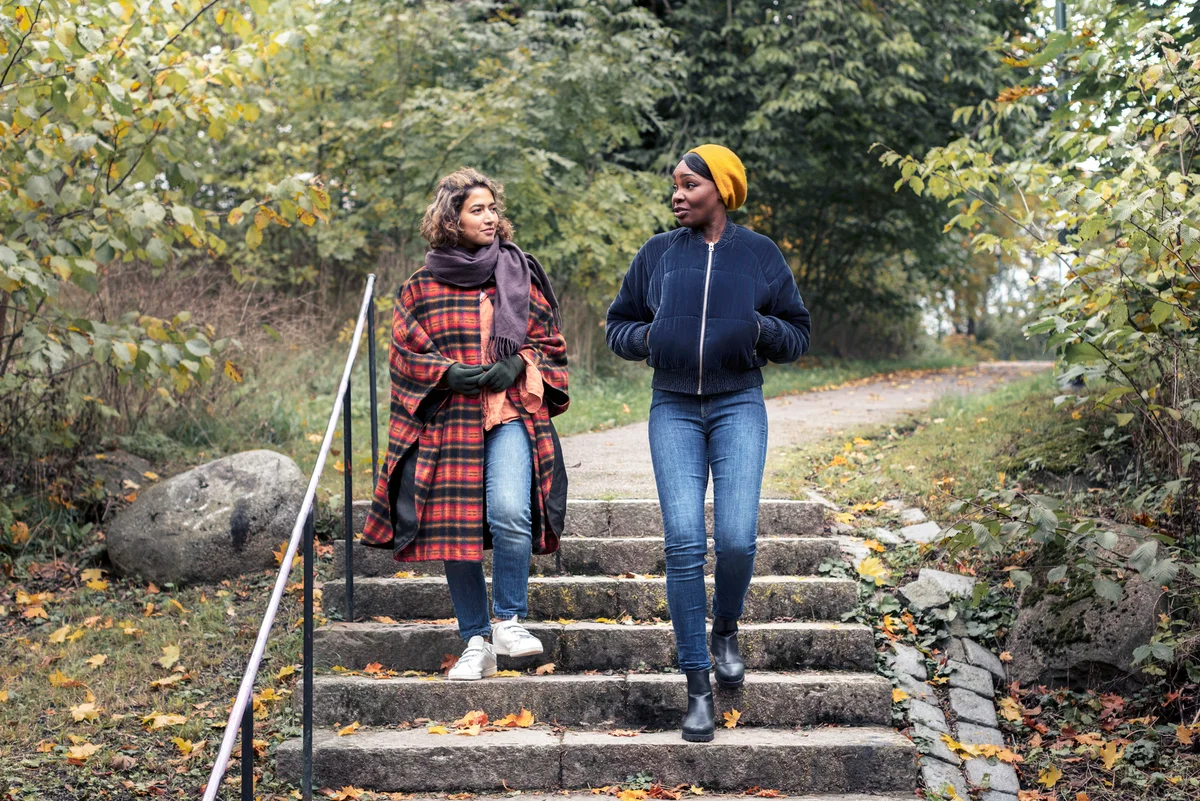 Two young women walking in park after Thanksgiving lunch