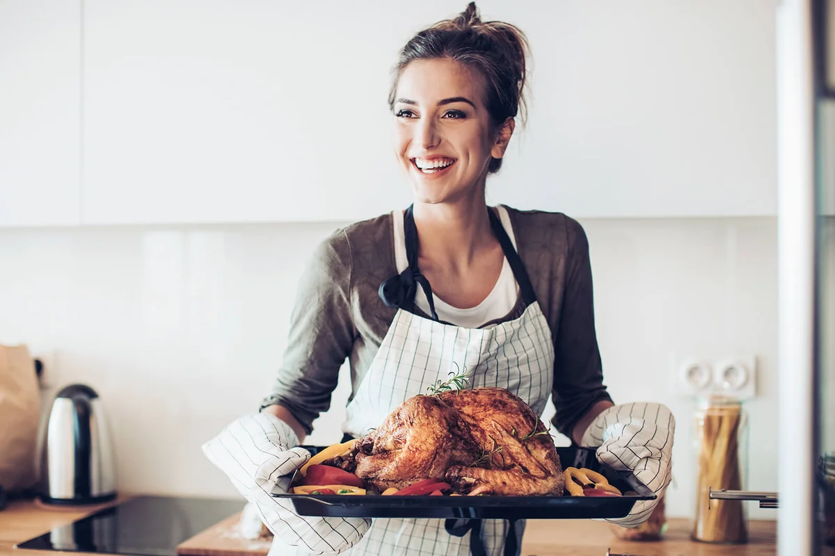 Smiling woman holding a tray with roasted turkey
