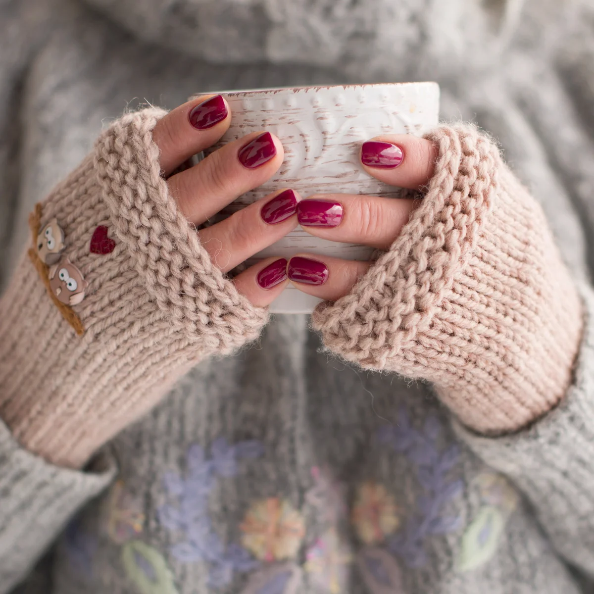 Woman wearing cozy fingerless gloves and holding a cup of hot chocolate