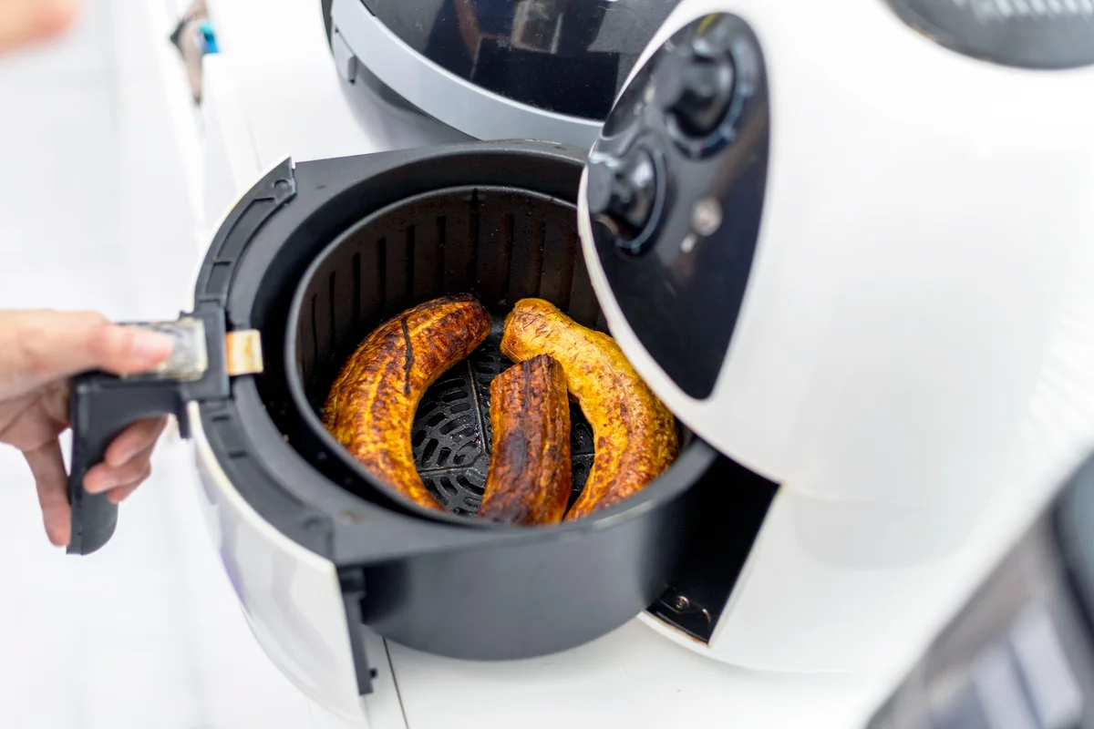 Woman opening the air fryer with some bananas ready for dinner