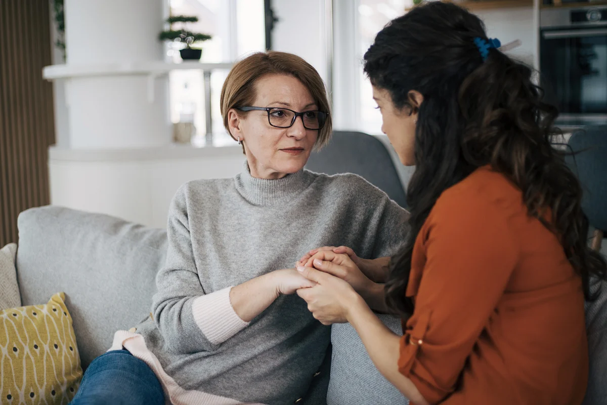 Mother and daughter talking to each other and holding hands
