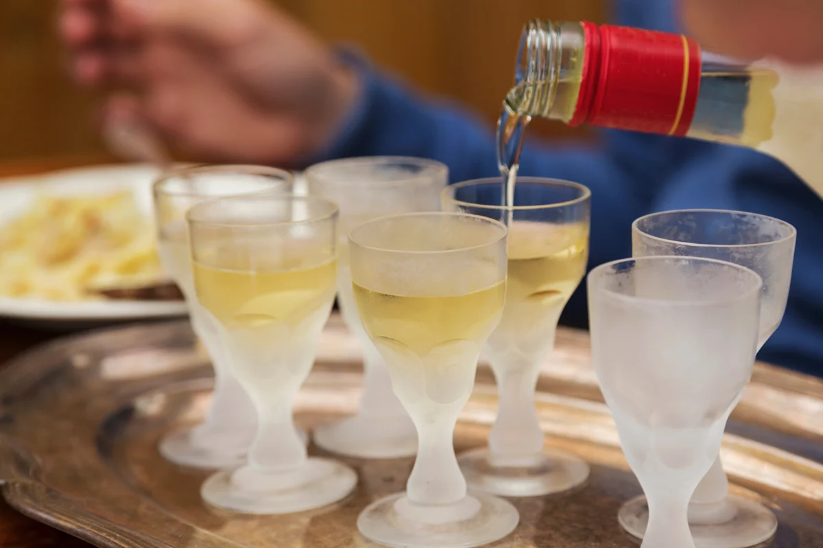 Pouring Aquavit into frosted glasses