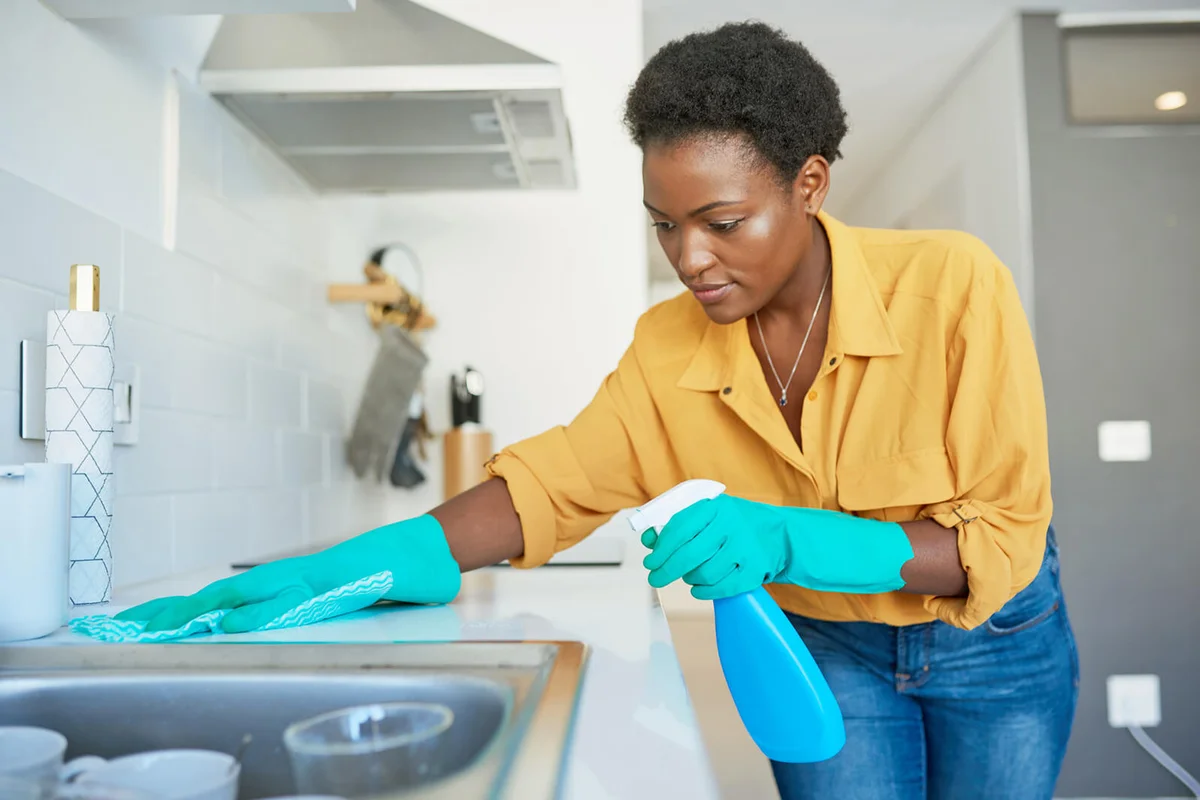 young woman cleaning a kitchen counter at home