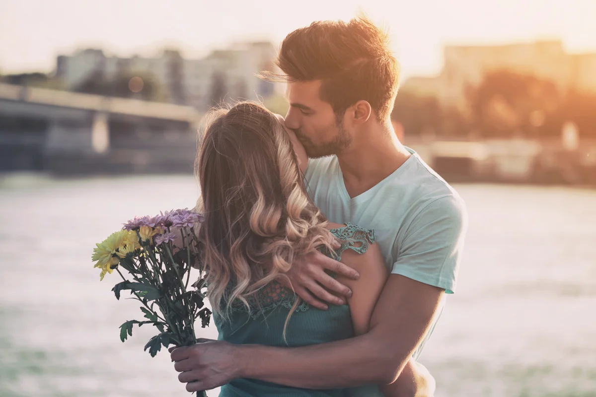 Young man giving flowers to his girlfriend outdoors
