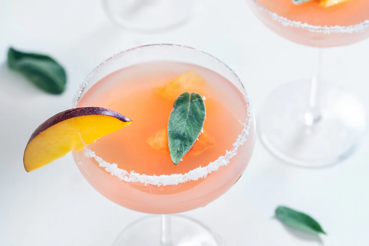 Bellini cocktails with peach fruit and sage leaves