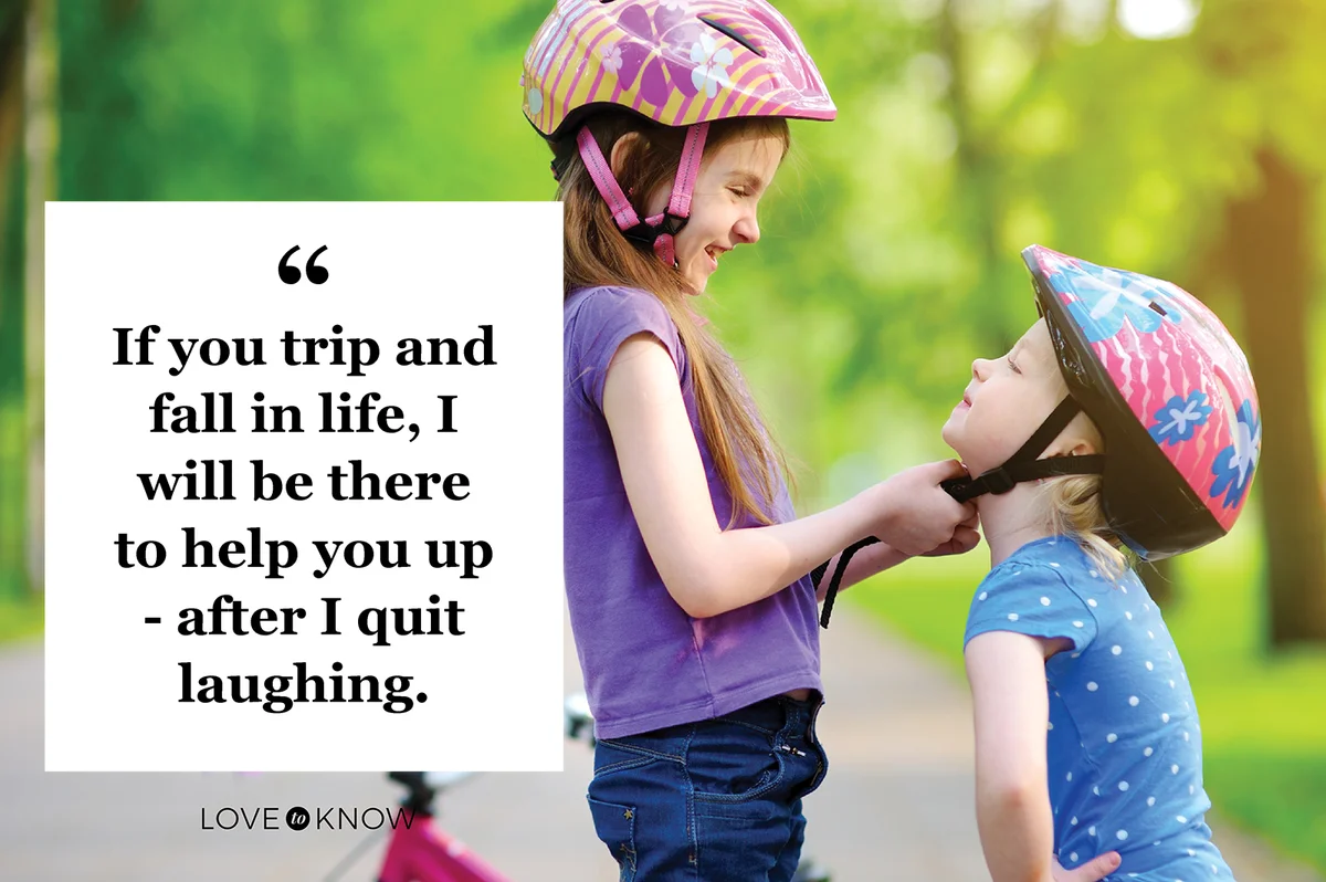 Adorable girl helping her sister to put a bicycle helmet on