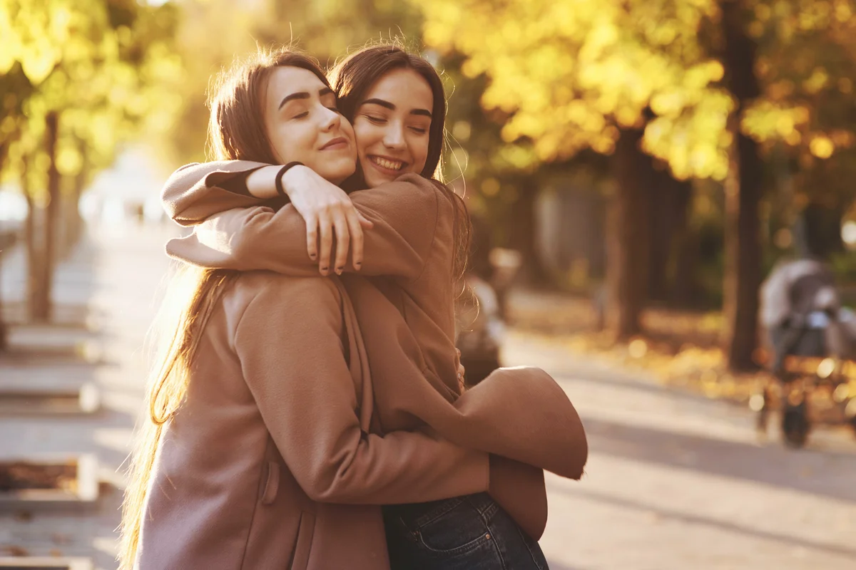 Sister hugging in the park at fall