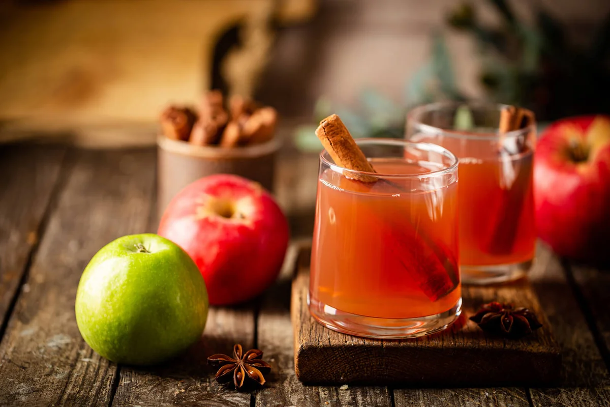 Glass of fresh apple juice with cinnamon and red apples