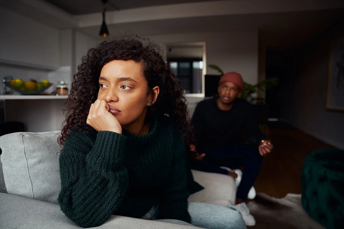 woman ignoring boyfriend while fighting on the sofa in modern apartment