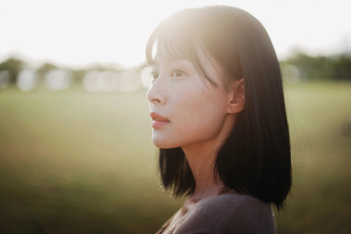 Carefree and serene young Asian woman relaxing in the park
