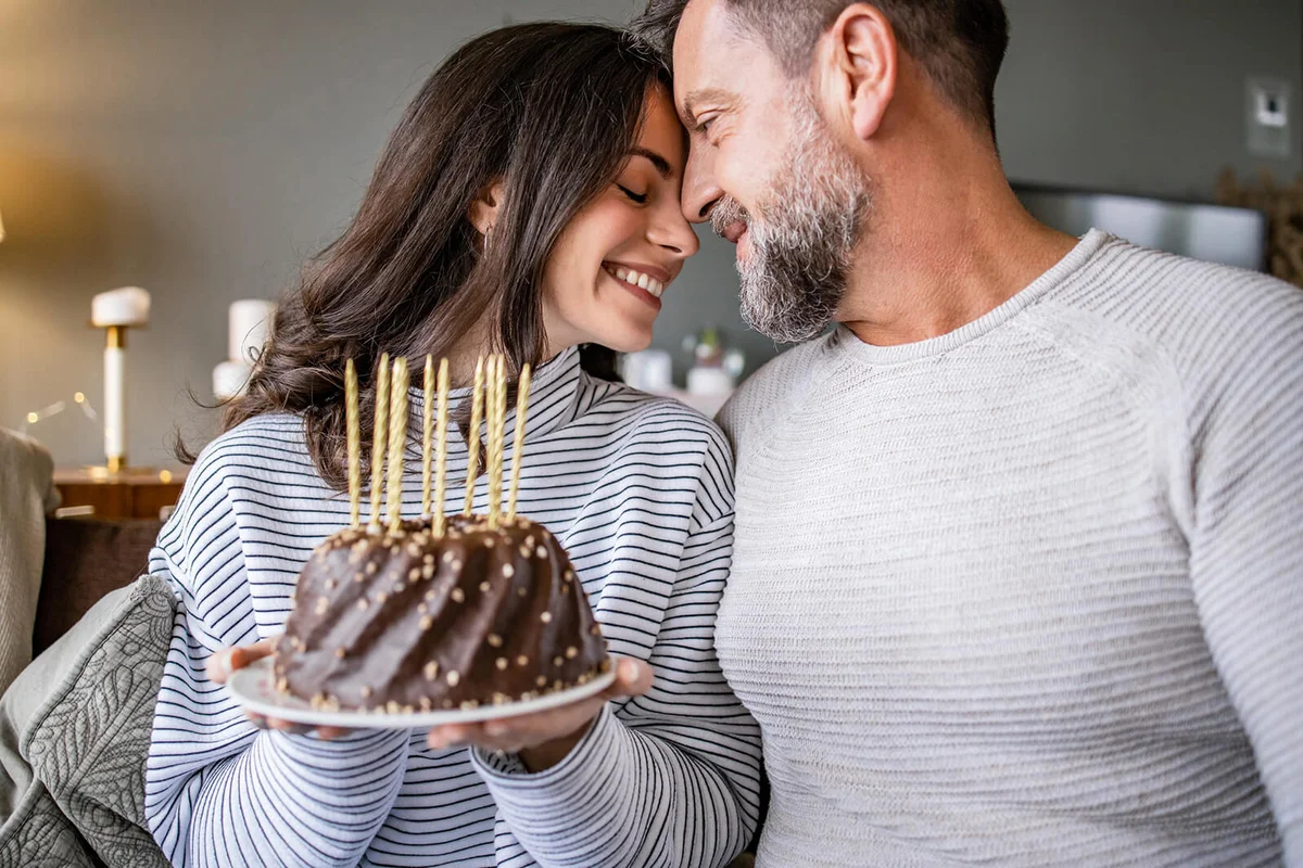 Romantic couple holding a birthday cake at home