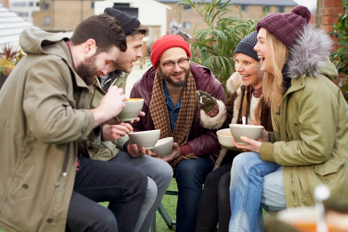 Friends eating soup, sitting together outside