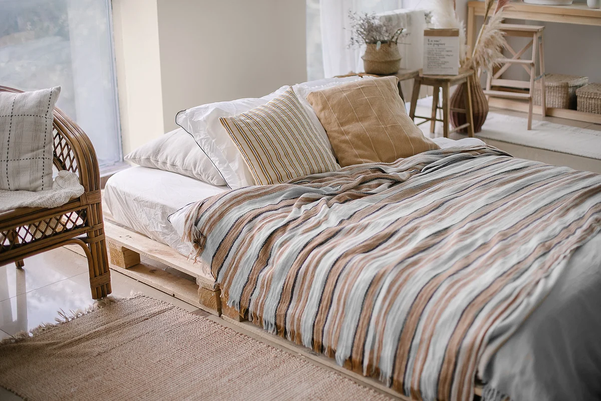 Cozy bedroom. Bed with pillows and striped blanket at cozy light bedroom