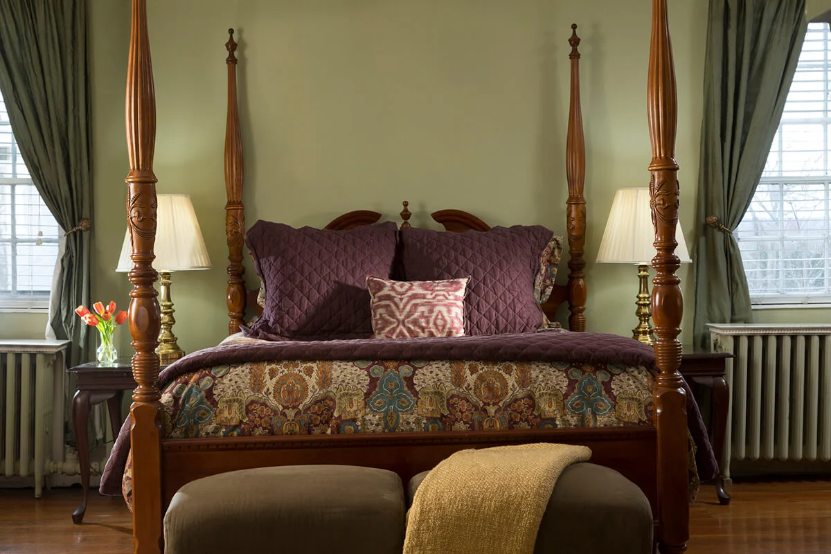 Straight-on view four-poster bed with green walls