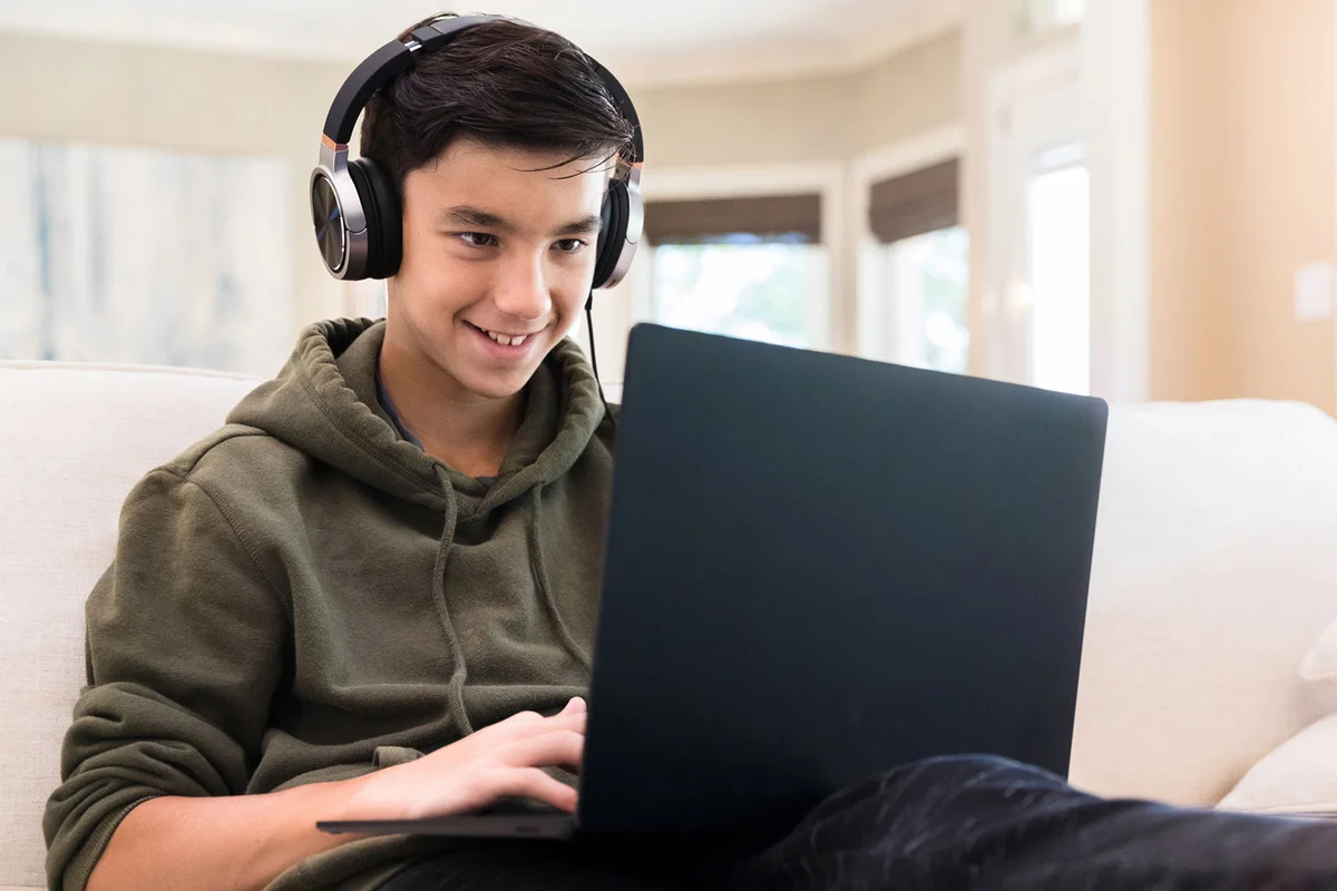 teenage boy playing game on laptop