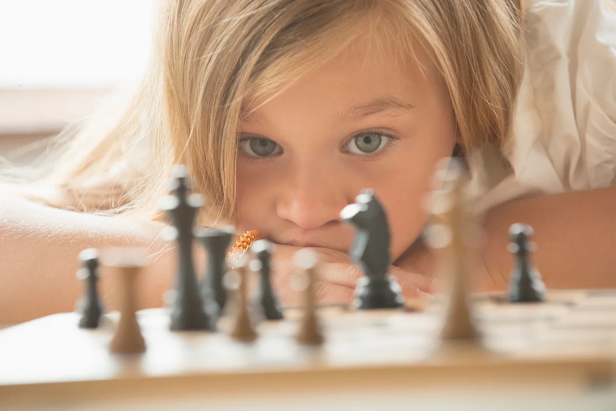 girl examining chess game board