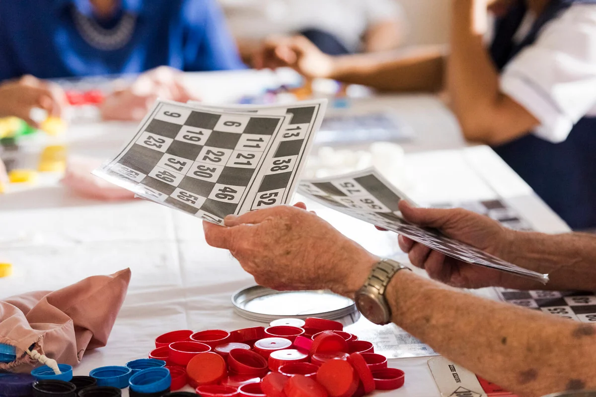 senior mans hands passing out number cards for a game of bingo