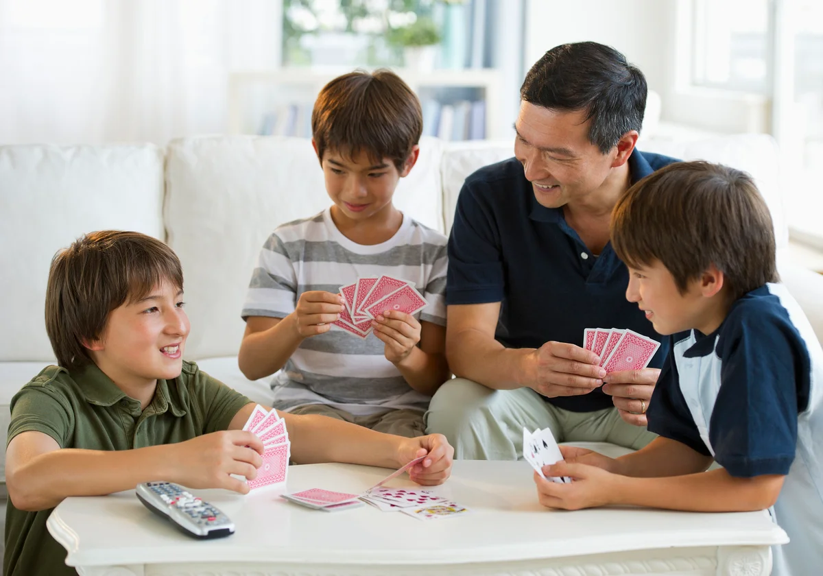 Father and sons playing Rummy card game