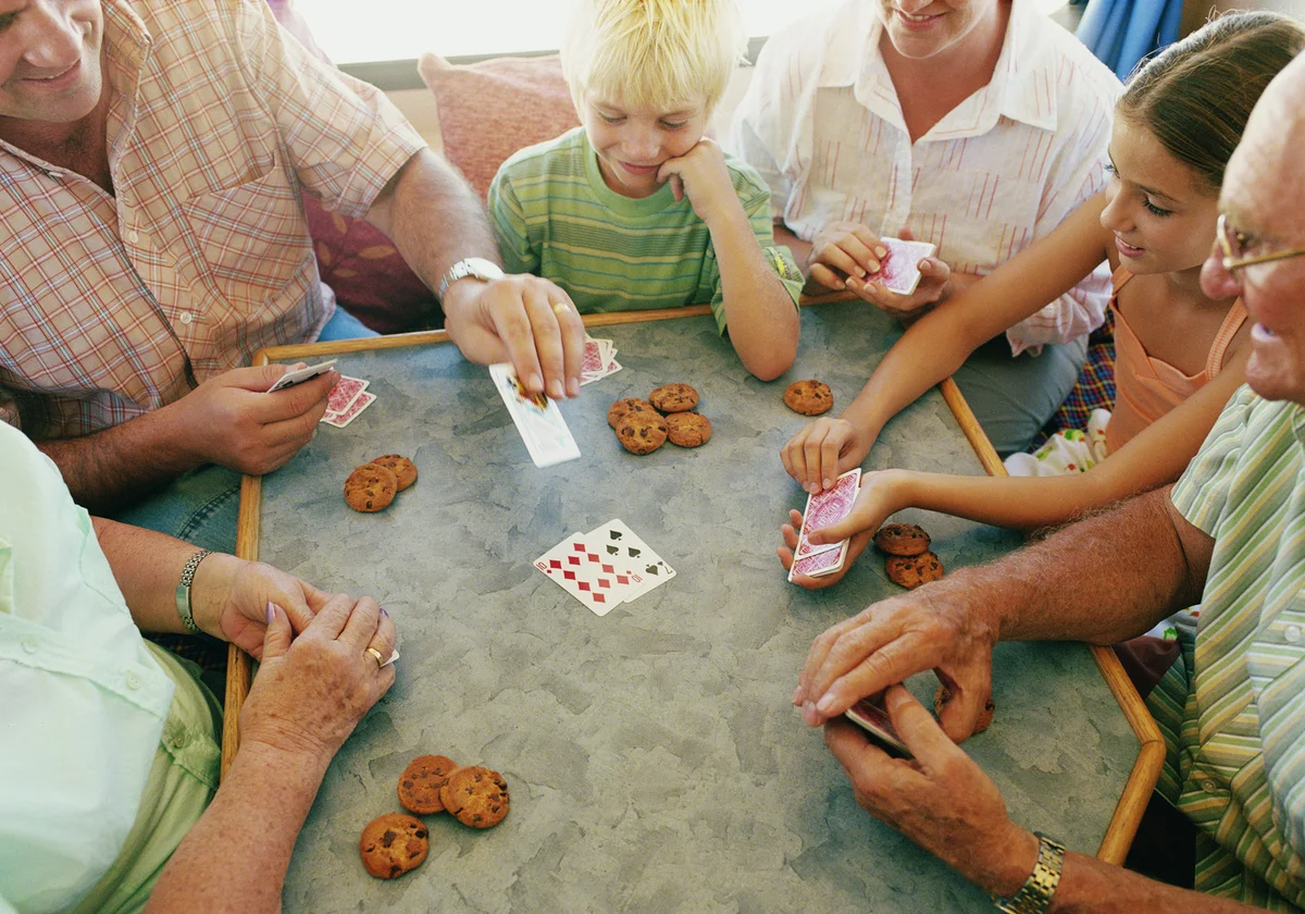 family gathered around table playing Play or Pay card game