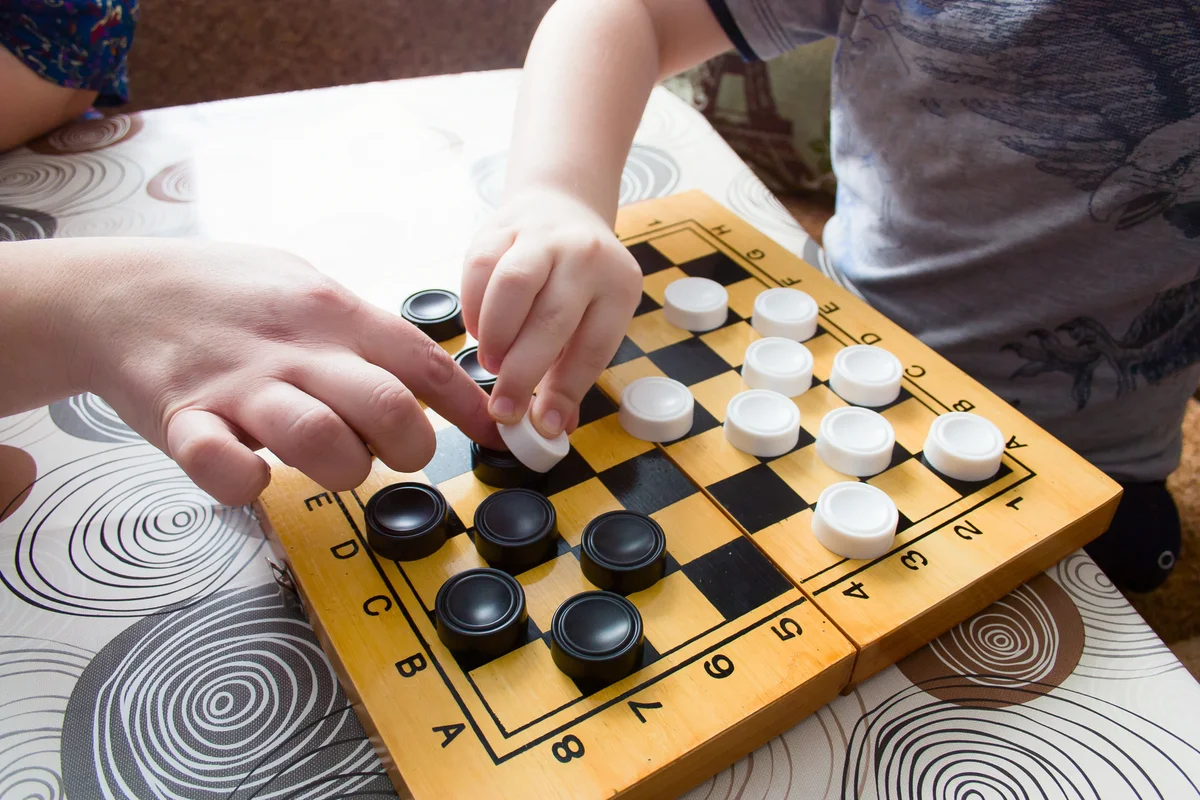 Woman and kid playing checkers at home
