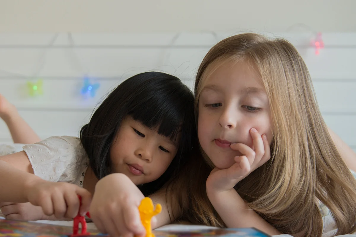 Girls playing a table game in a bed