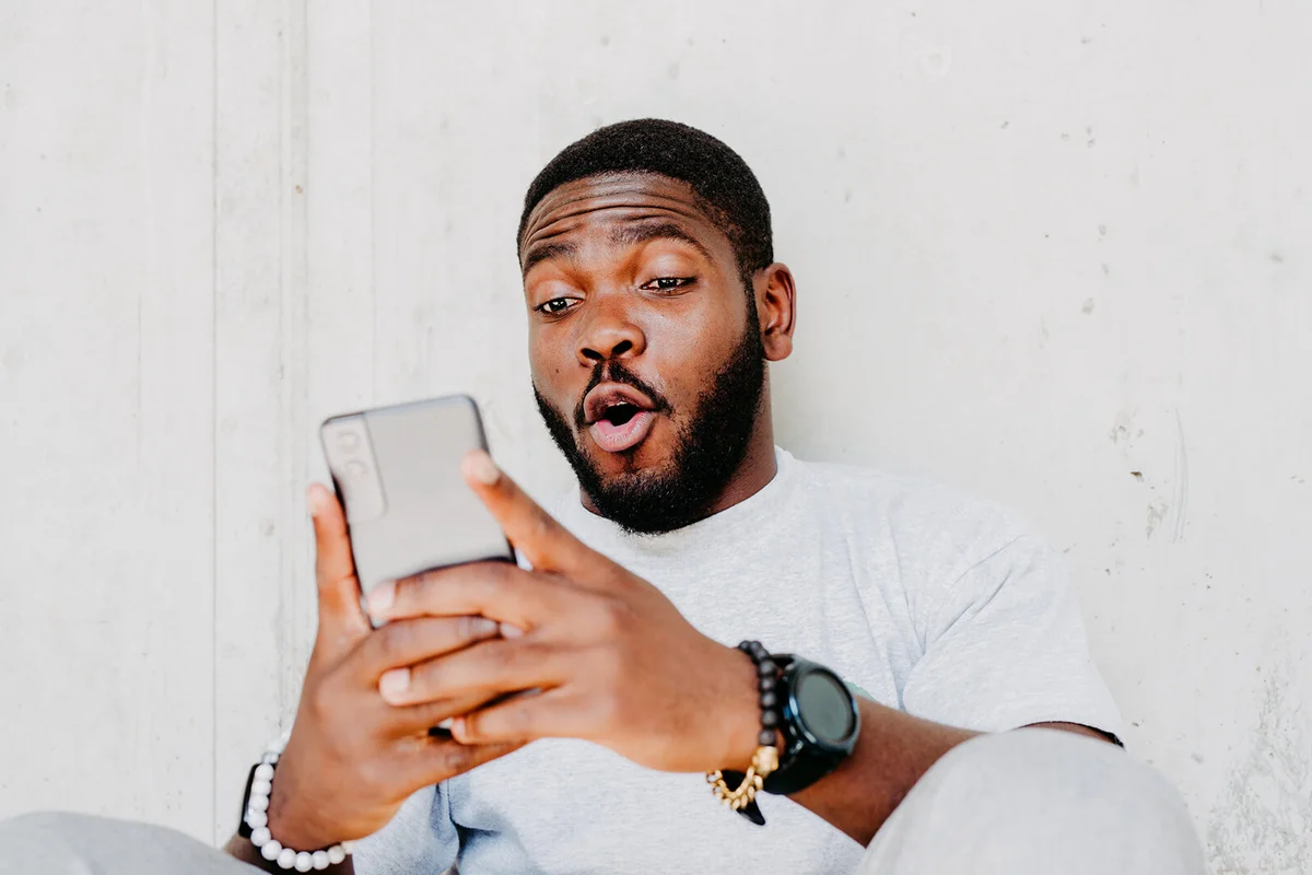 man with surprised facial expression hold smartphone in his hand