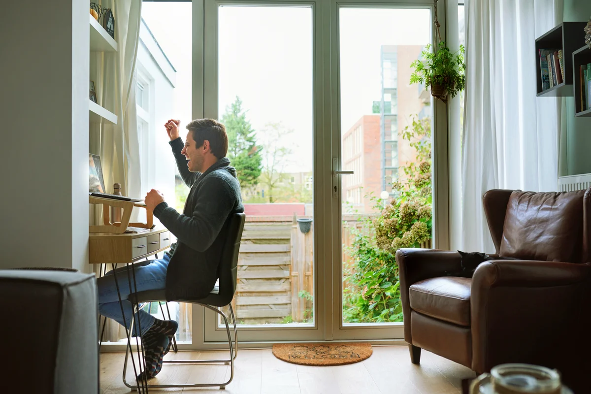 Shot of a young man using a laptop and cheering at home