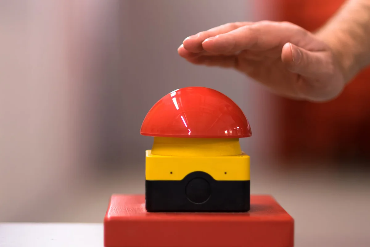 Hand above a red emergency button
