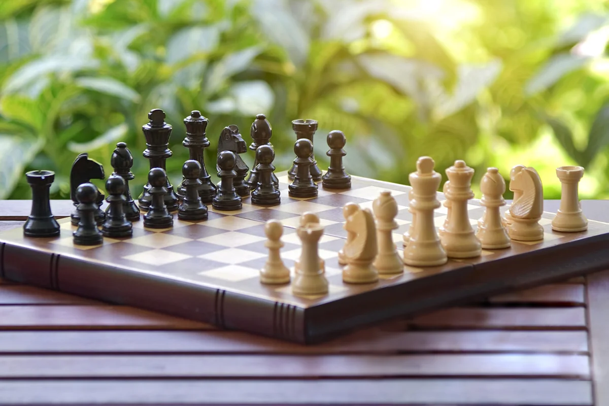 Chessboard and chess pieces on the table in the garden