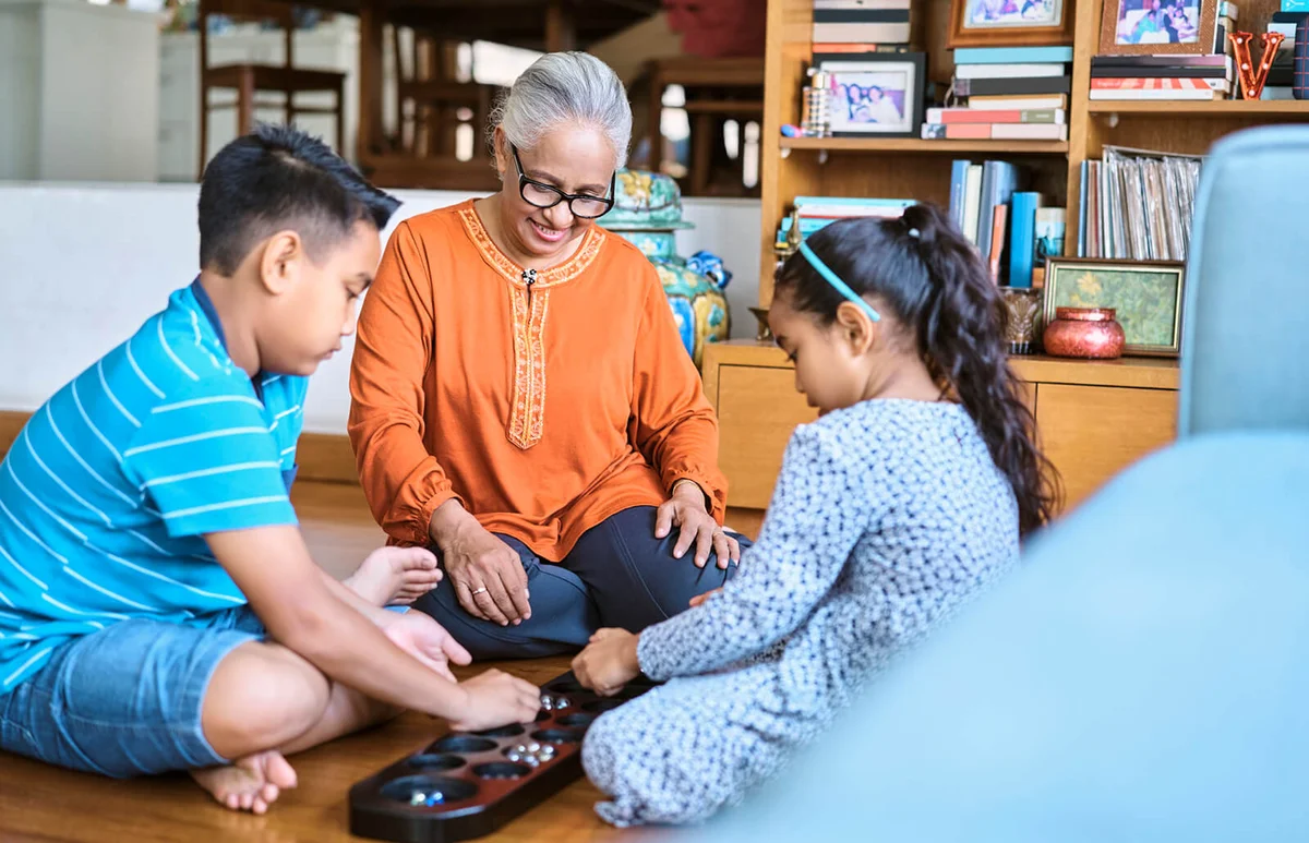 Woman looking at kids playing Mancala board game