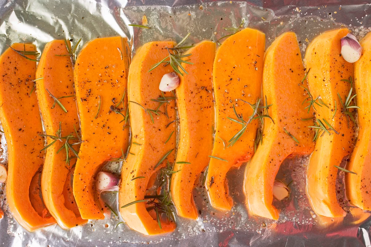 Pumpkin slices with rosemary and garlic on aluminium foil