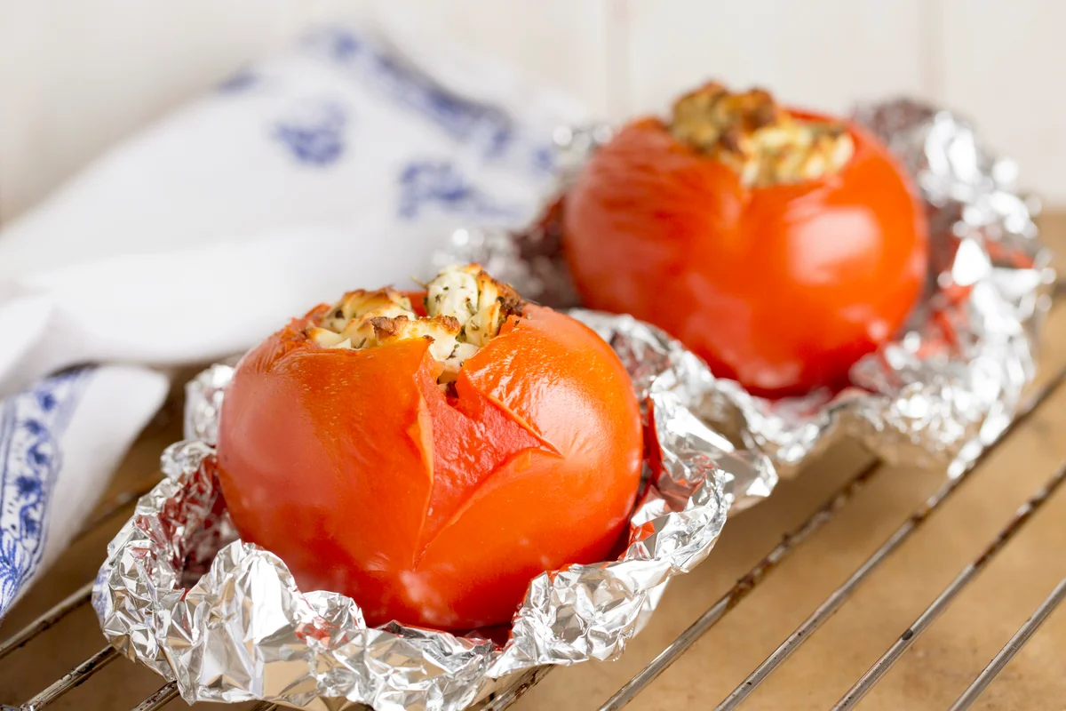 Stuffed grilled tomatoes with feta cheese in tin foil