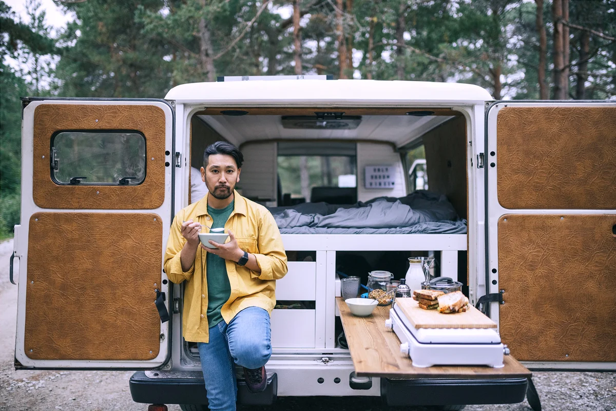 Man eating breakfast next to his camper van