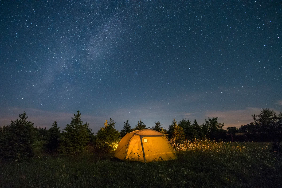 Illuminated camping tent under starry sky