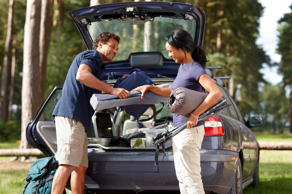Couple unpacking their car on camp site