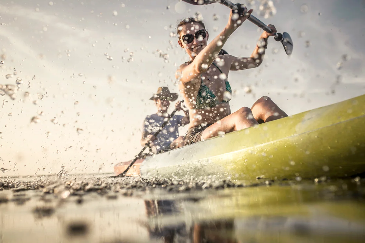 Couple rowing canoe on still lake