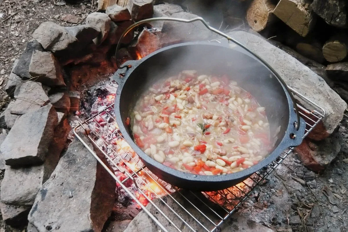 Bean stew in dutch oven cooking over campfire