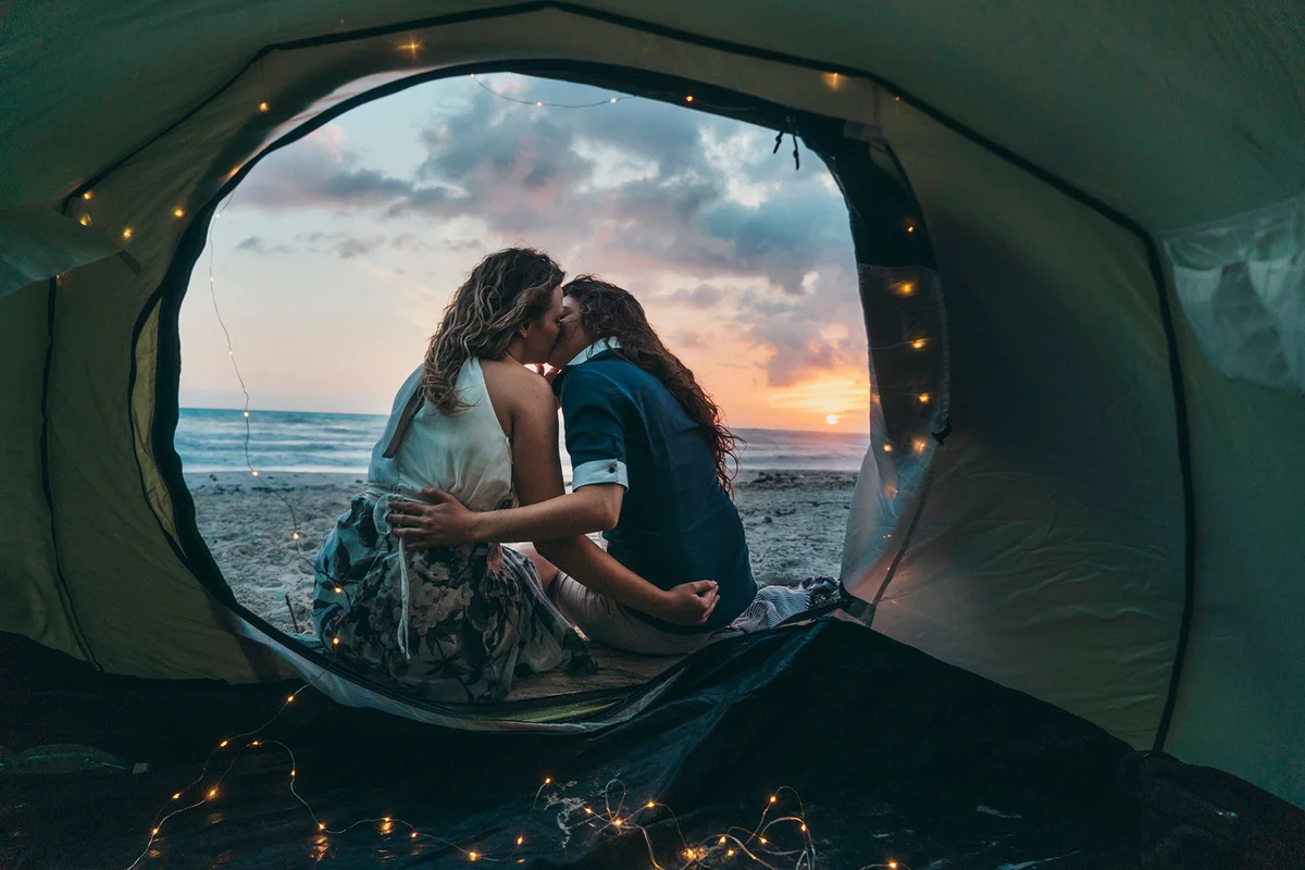 Young adult couple admiring the sunset in a tent on the beach