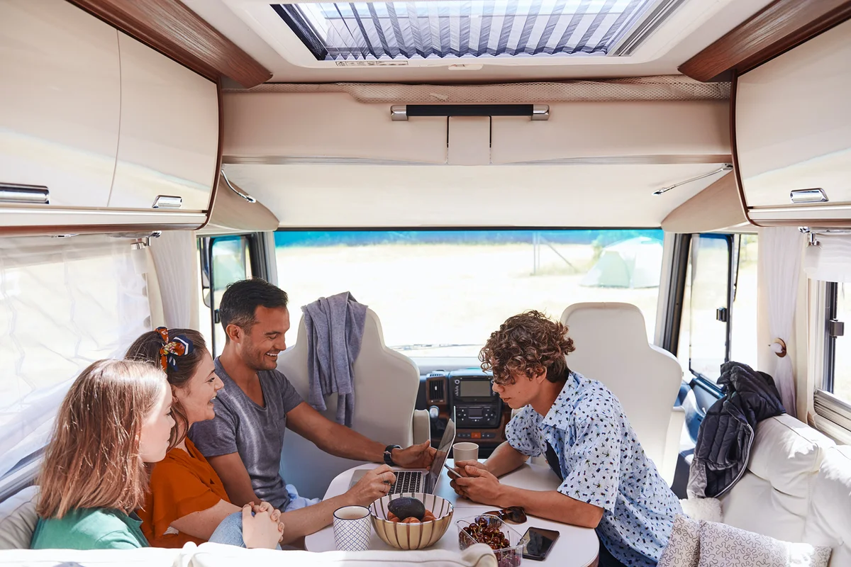 family looking at laptop while sitting in camper van