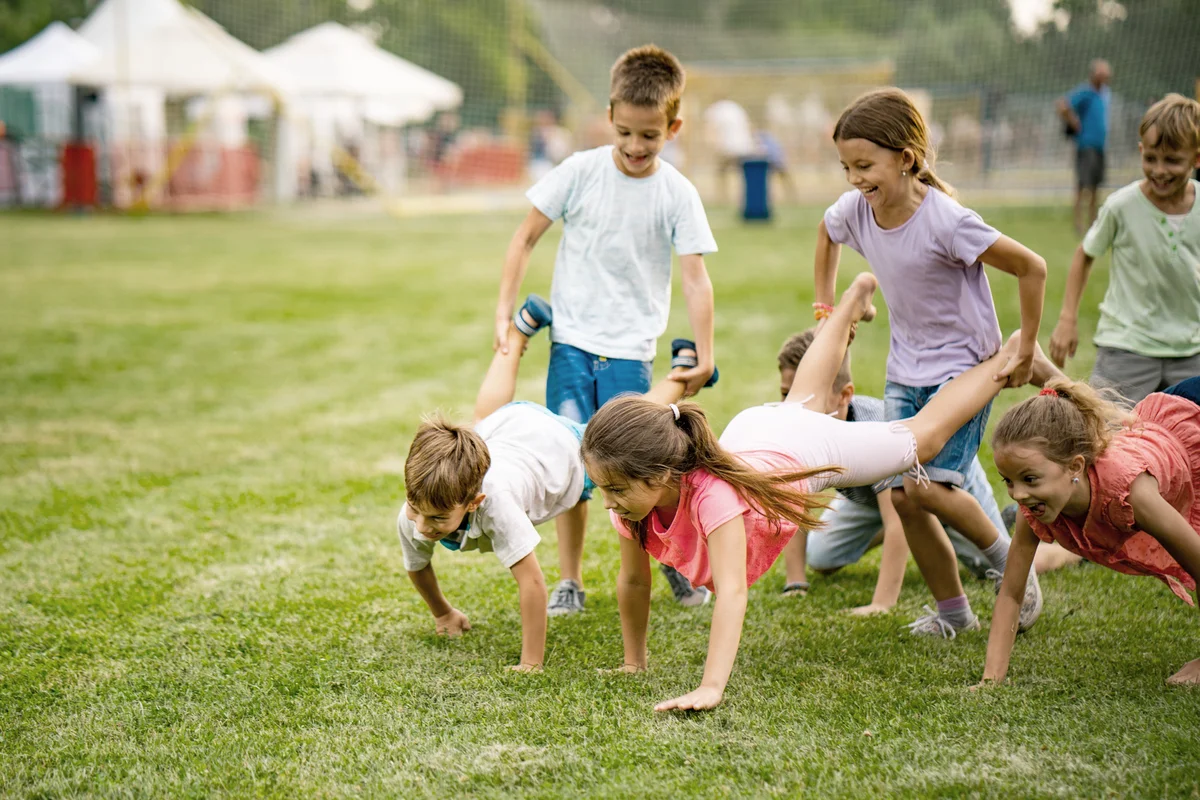 Playful children having fun in wheelbarrow race