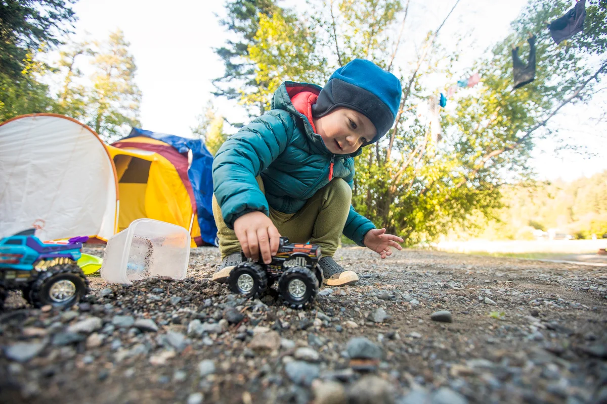 Toddler boy driving monster trucks through dirt and rocks