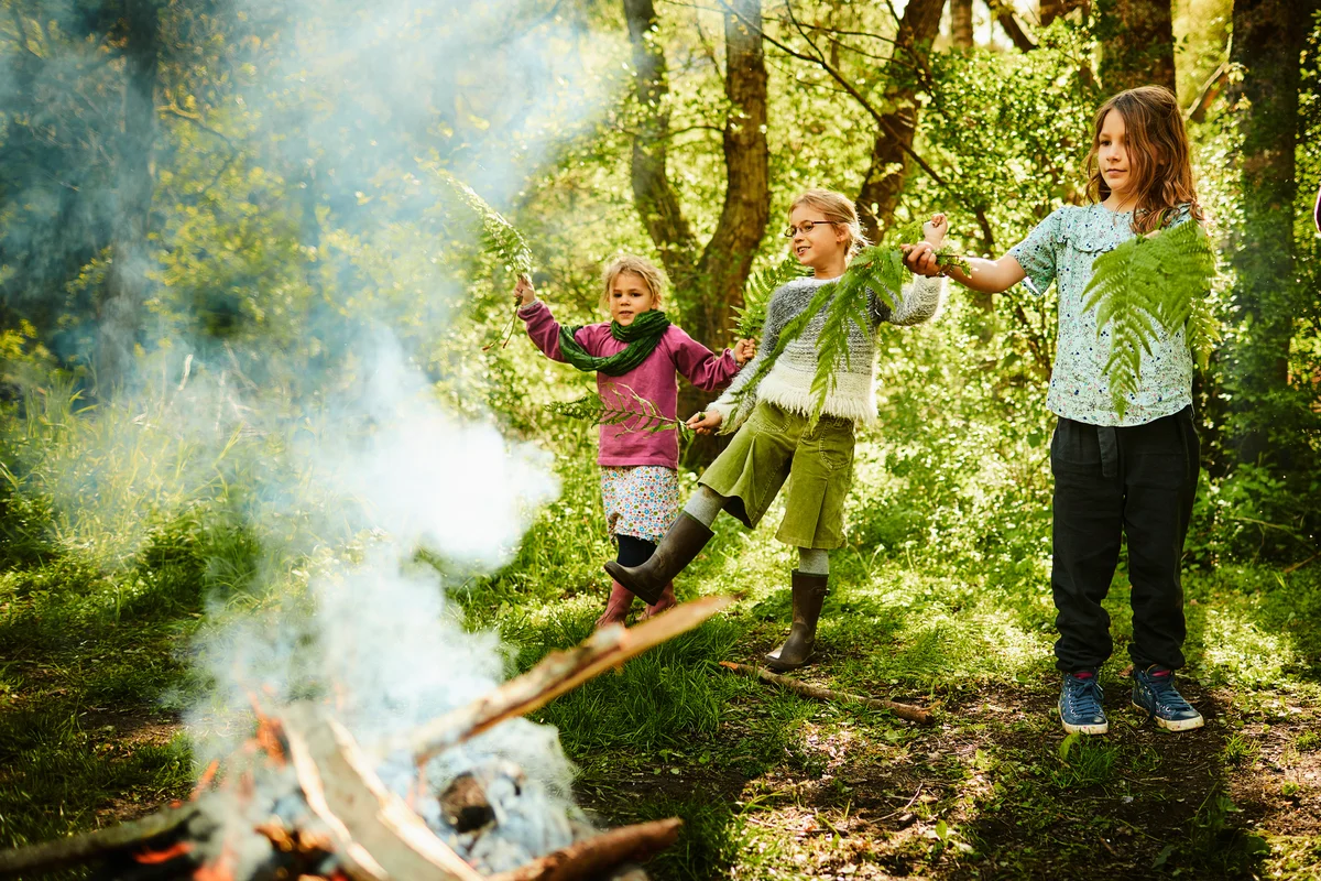 Happy girls standing at camp fire in the nature