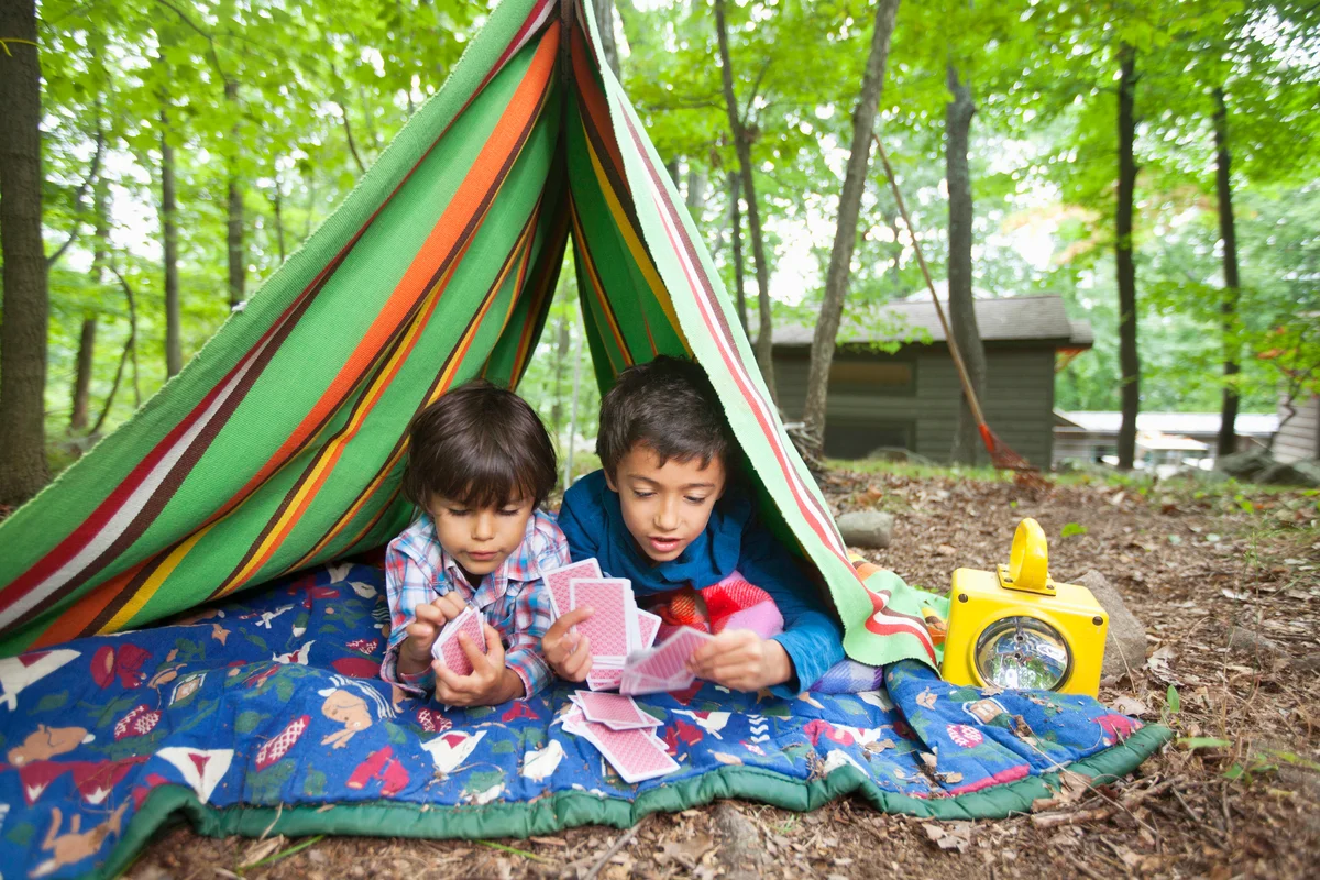 Boys playing card game in blanket fort