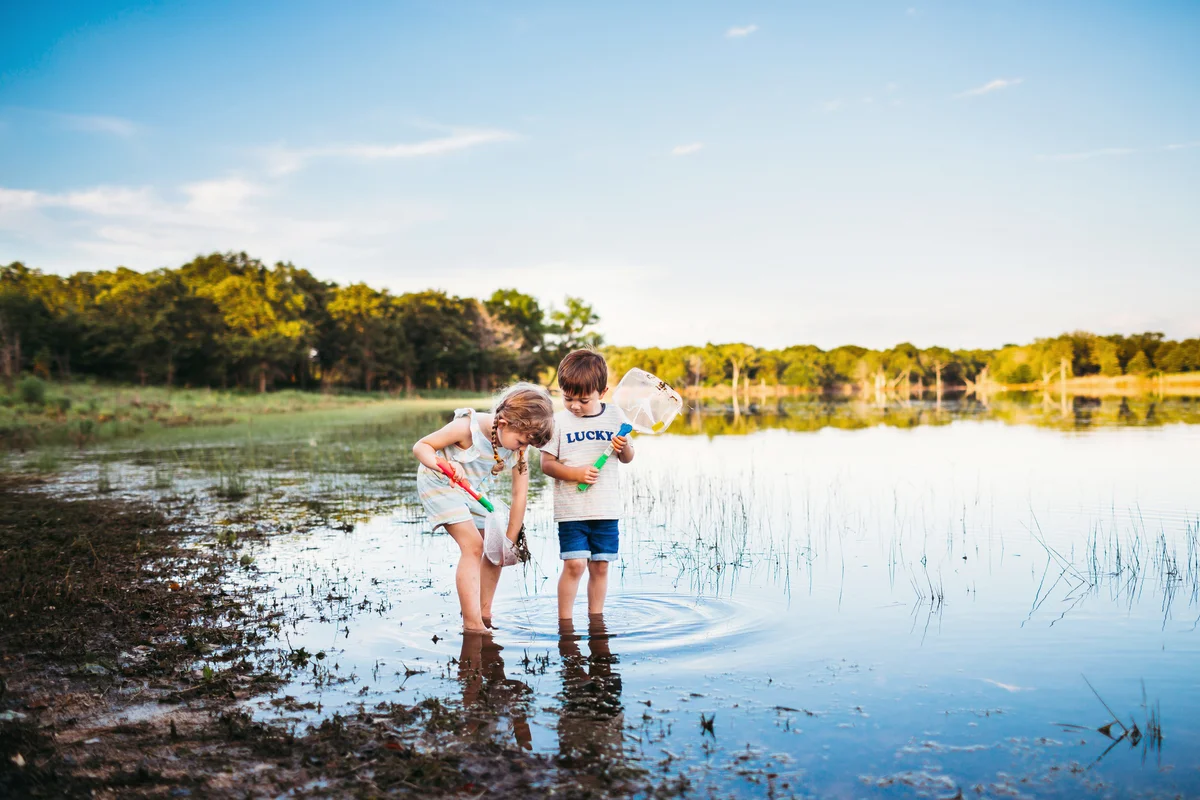 Young girl and boy looking at fish they caught in a net at the lake