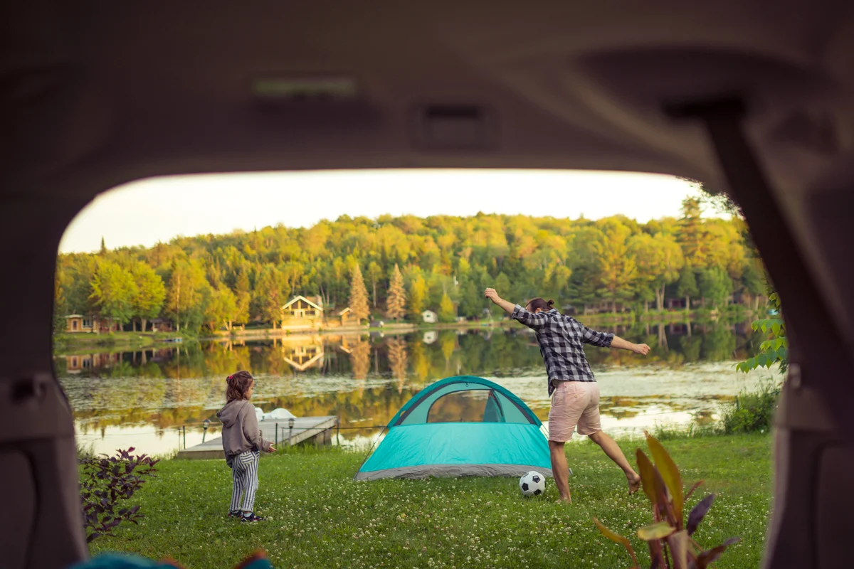 Father and daughter playing soccer by the lake