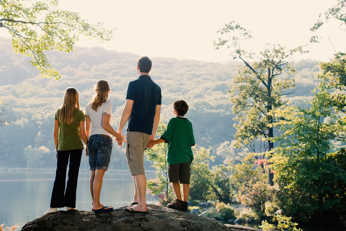 Family standing together looking at view of lake in nature