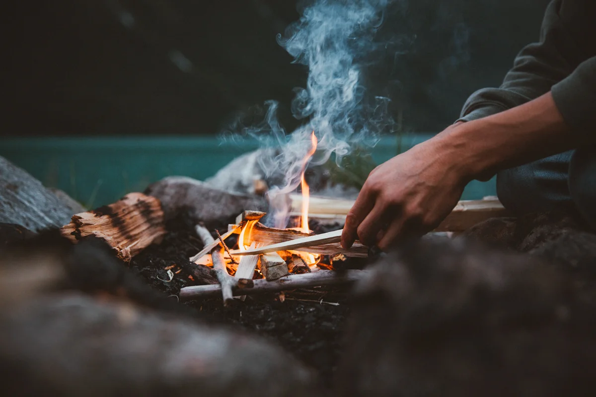 Midsection Of Man Sitting By Campfire