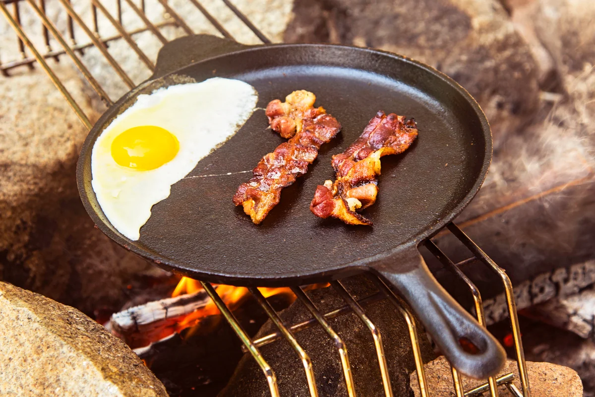 Egg and bacon in skillet over fire