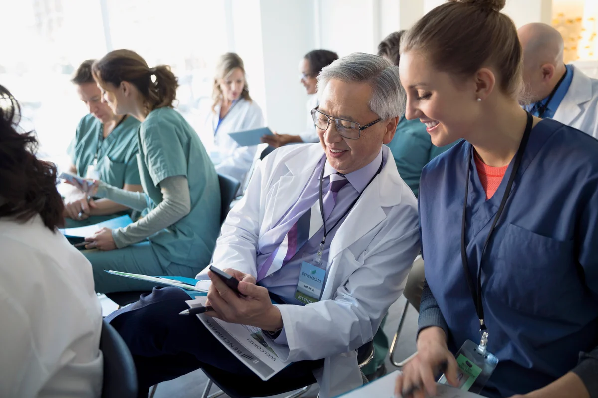 Doctor showing cell phone to nurse seminar audience