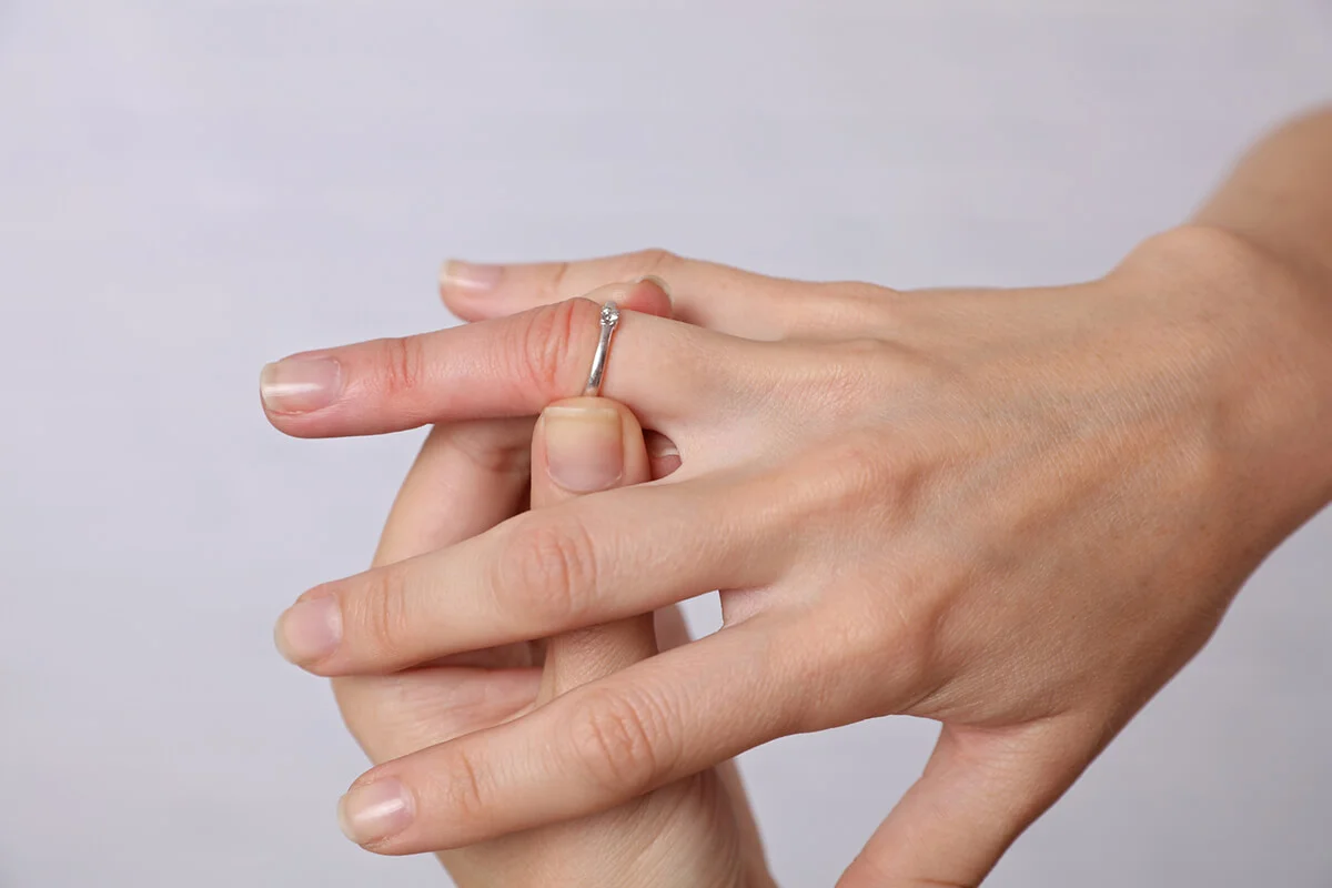 Woman traing to remove stuck ring off a swollen finger